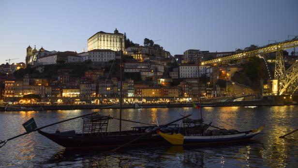 Porto bei Nacht, kleine Boote auf dem Douro im Vordergrund, Blick auf die beleuchtete Brücke Ponte Dom Luis I