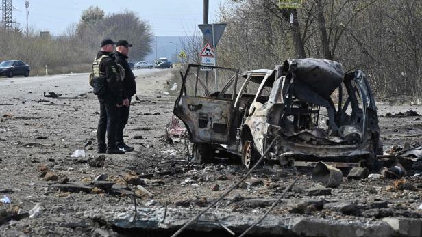 Ukrainische Polizisten in Charkiw untersuchen ein durch eine Rakete zerstörtes Auto.