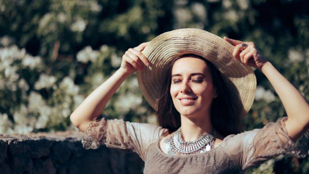 Eine Frau mit Hut genießt die Sonne.