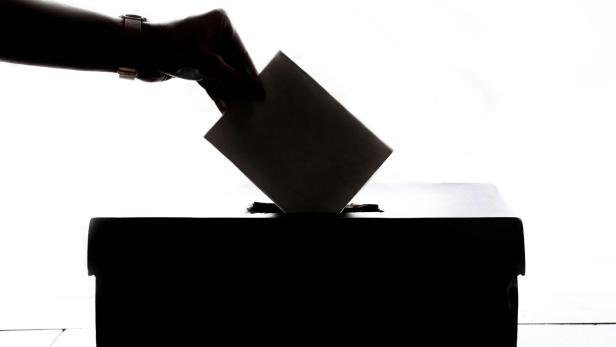Ein Brief wird in eine Wahlurne gesteckt