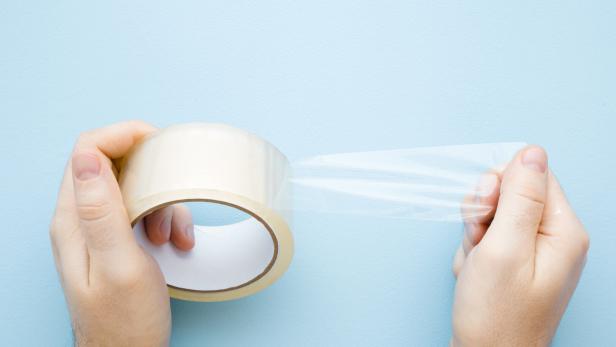 Eine Rolle transparentes Klebeband wird von zwei Händen gehalten.