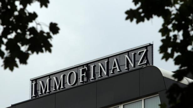 Das Schild „IMMOFINANZ“ auf dem Dach eines Gebäudes, teilweise von Blättern verdeckt.