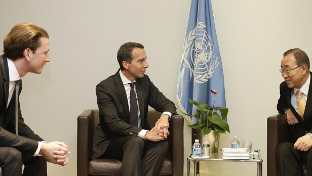 Drei Männer sitzen vor einer UN-Flagge und unterhalten sich.