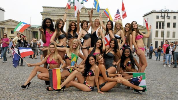 Eine Gruppe von Frauen in Badebekleidung posiert mit Flaggen vor dem Brandenburger Tor in Berlin.