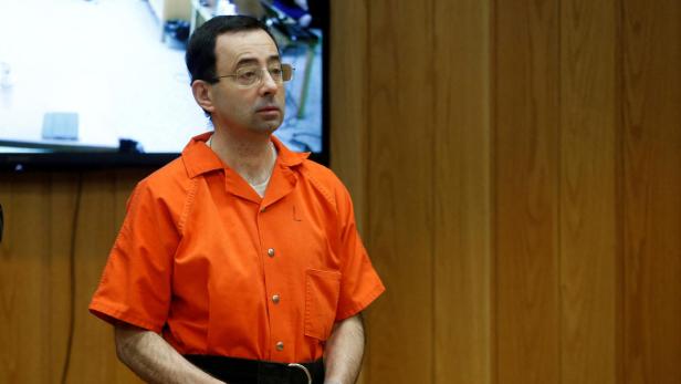 FILE PHOTO: Larry Nassar, a former team USA Gymnastics doctor who pleaded guilty in November 2017 to sexual assault charges, stands in court during his sentencing hearing in the Eaton County Court in Charlotte