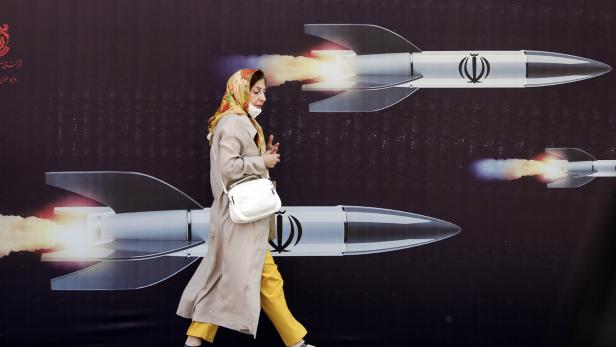 Ein Frau geht an einem Wandbild mit Raketen vorbei