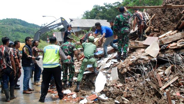 Helfer und Rettungskräfte arbeiten inmitten von Trümmern nach einem Erdrutsch.