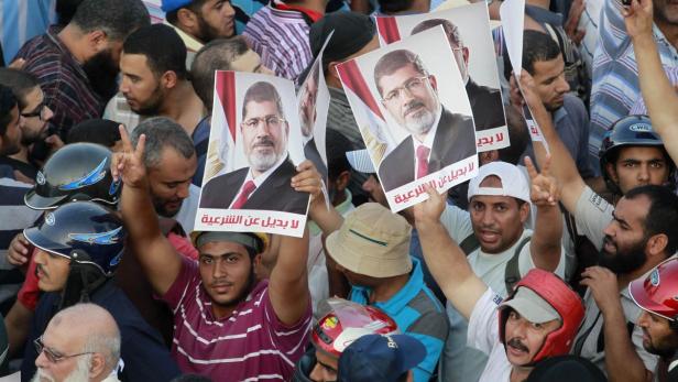 Supporters of deposed Egyptian President Mohamed Mursi hold posters during a protest outside Rabaa Adawiya mosque in Cairo July 9, 2013. Egypt&#039;s interim President Adli Mansour on Tuesday named liberal economist and former finance minister Hazem el-Beblawi as prime minister in a transitional government, as the authorities sought to steer the country to new parliamentary and presidential elections. The posters read, &quot;No substitute for the legitimacy.&quot; REUTERS/Louafi Larbi (EGYPT - Tags: POLITICS CIVIL UNREST)