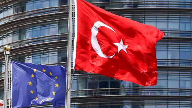 Symbolbild für den EU-Türkei-Deal: EU- und Türkeiflaggen wehen vor einem modernen Glashochhaus