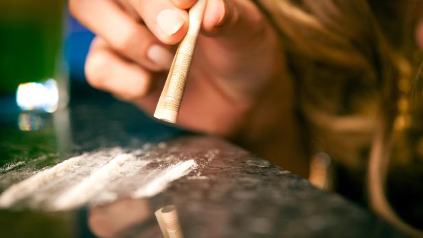 Young woman snorting cocaine with rolled up dollar
