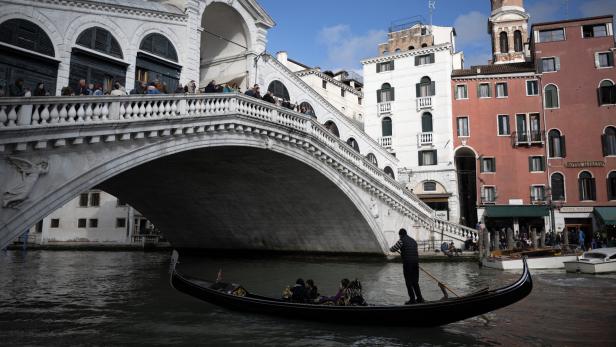 Eine Gondel passiert die Rialto-Brücke in Venedig