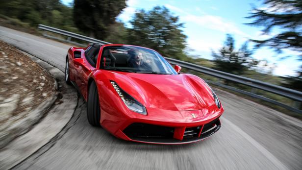 Ein roter Ferrari fährt auf einer kurvenreichen Straße.