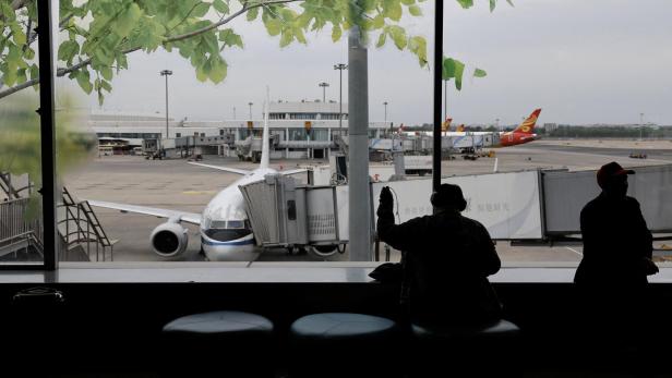 Passagiere blicken vom Flughafen aus auf ein Flugzeug