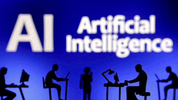 Symbolbild KI:  Schattenschnitt von Menschen, die vor dem Schriftzug "Artificial Intelligence" an Laptops sitzen