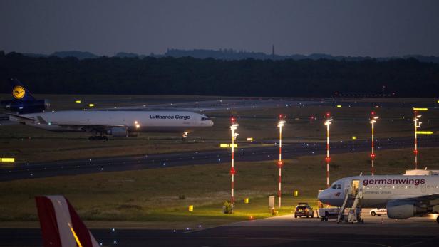 Ein Lufthansa Cargo Flugzeug auf einer beleuchteten Startbahn bei Nacht.