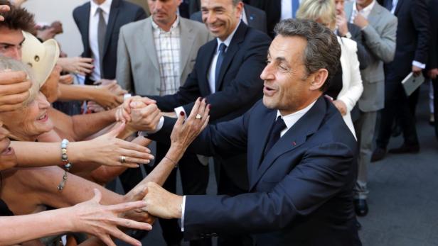 Nicolas Sarkozy schüttelt Hände in einer Menschenmenge.