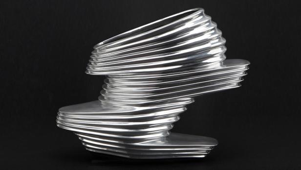 Eine silberne, spiralförmige Skulptur vor einem schwarzen Hintergrund.