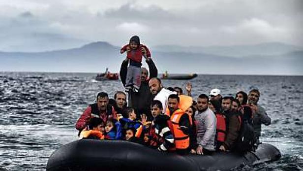 Eine Gruppe von Menschen, darunter Kinder, sitzt in einem Schlauchboot auf dem Meer.