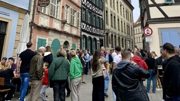 Menschen stehen in der Bamberger Innenstadt vor einer Bierbrauerei an