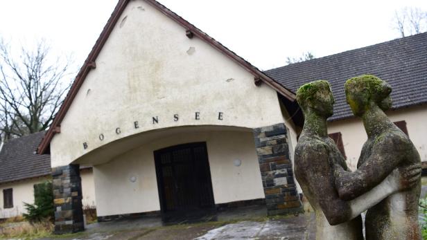 Vor dem Gebäude "Bogensee" steht eine moosbewachsene Skulptur eines Paares.