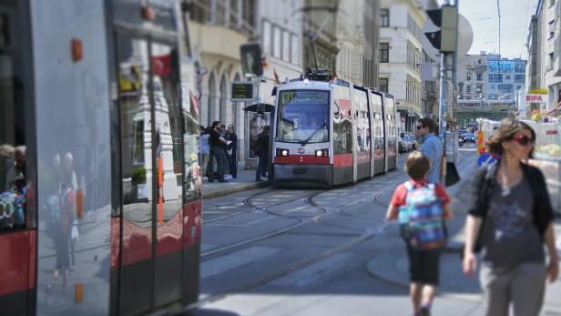 Eine Straßenbahn der Linie 33 hält in einer belebten Straße in Wien.