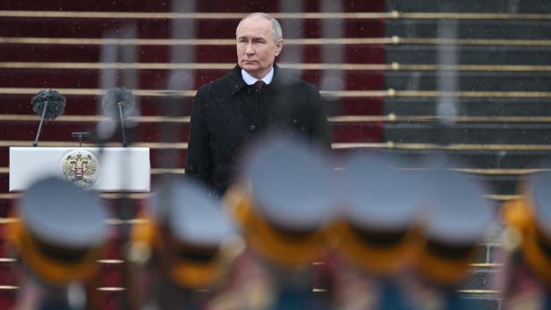 Putin blickt bei einer Zeremonie Soldaten mit Waffen entschlossen an