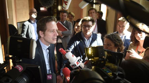 Ein Mann im Anzug spricht in eine Ansammlung von Mikrofonen.