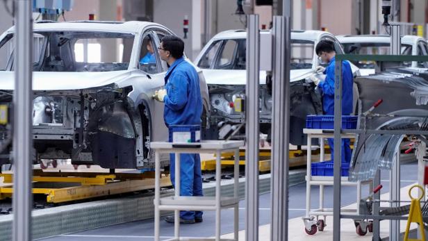 FILE PHOTO: Employees work on assembly line of SAIC Volkswagen MEB electric vehicle plant in Shanghai