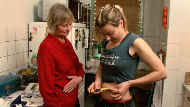 Eine Frau spritzt sich Insulin, während eine ältere Frau zusieht.