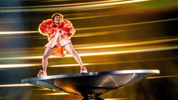 Der Schweizer Song-Contest-Vertreter Nemo in einem rosa Rüschenkostüm auf einer großen Balancierscheibe