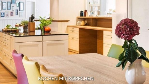 Eine moderne Küche mit Kochinsel, Esstisch und farbigen Stühlen.