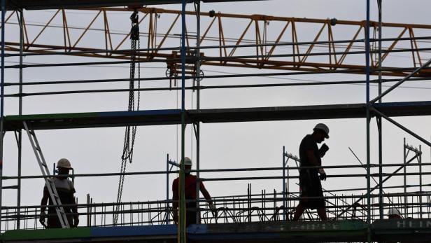 FILE PHOTO: Builders work on scaffoldings at the construction site for a shopping mall in Monheim