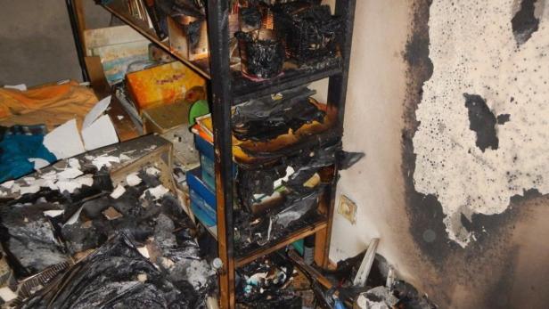 Ein Zimmer mit Brandschäden an einem Regal und der Wand.