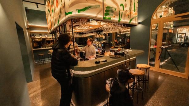 Ein Barkeeper serviert einem Gast in einer Bar einen Drink.