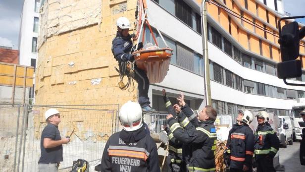 Ein Feuerwehrmann wird an einem Seil hängend von anderen Feuerwehrleuten gesichert.