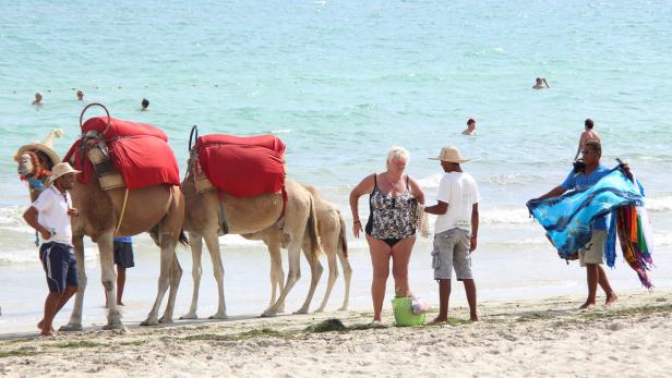 Am Strand werden Touristen Kamelritte und bunte Tücher angeboten.