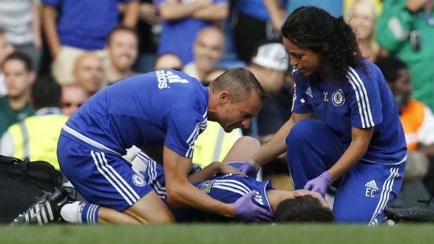 Zwei Sanitäter kümmern sich um einen verletzten Fußballspieler auf dem Spielfeld.