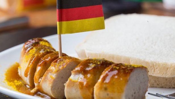 Auf einer Currywurst steckt eine Papierflagge mit den deutschen Farben Schwarz, Rot, Gold