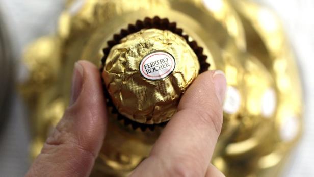 Eine Hand hält eine Praline von Ferrero Rocher.