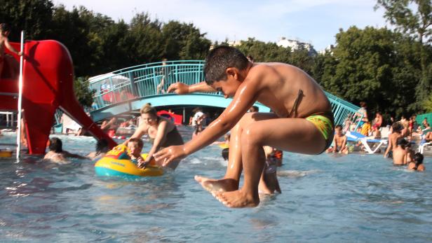 Ein Junge springt in einem Schwimmbad ins Wasser.