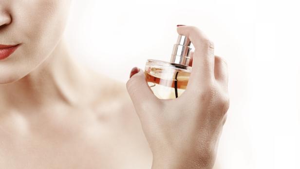 Eine Frau sprüht Parfüm auf ihren Hals.