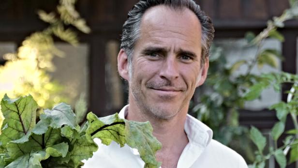 Ein Mann hält frisch geerntete Rote Bete in seinem Garten.