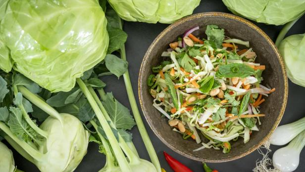 Coleslaw-Salat in einer braunen Schüssel mit Kohl und Kohlrabi rundum