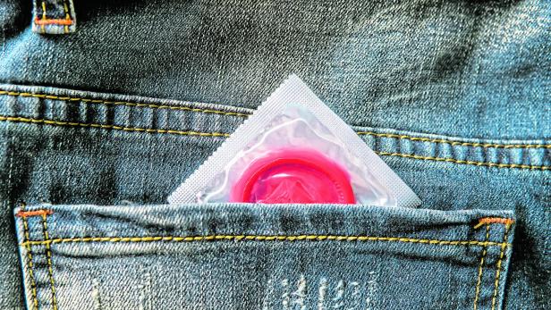 concept of safe sex. Condom in the pocket of a blue jeans