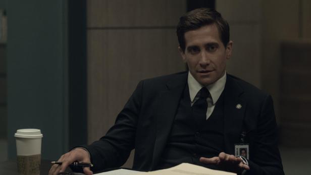 Jake Gyllenhall als Anwalt in der Serie "Aus Mangel an Beweisen", vor ihm liegte eine Aktenmappe am Tisch und ein Becher Kaffee