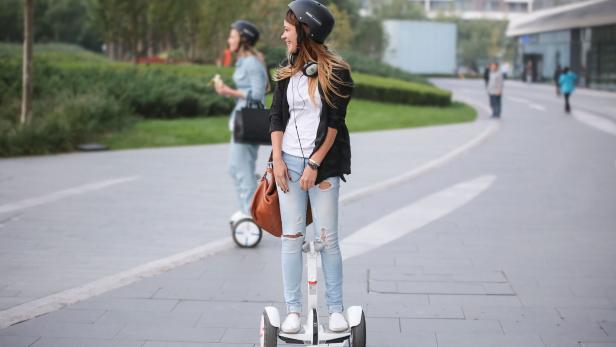 Eine junge Frau fährt mit einem Segway durch einen Park.