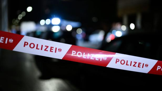 Absperrband mit der Aufschrift „Polizei“ vor unscharf beleuchteter Straße in der Nacht.