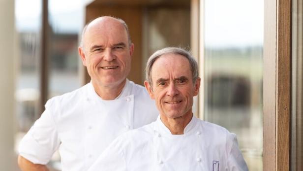 Zwei Köche in Kochuniformen stehen vor einem Restaurant.