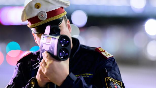 Ein Polizist in Uniform mit Mütze bedient ein Radargerät zur Geschwindigkeitsmessung.