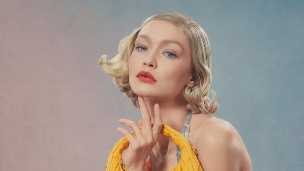 Gigi Hadid posiert mit einer gelben Miu Miu Handtasche.